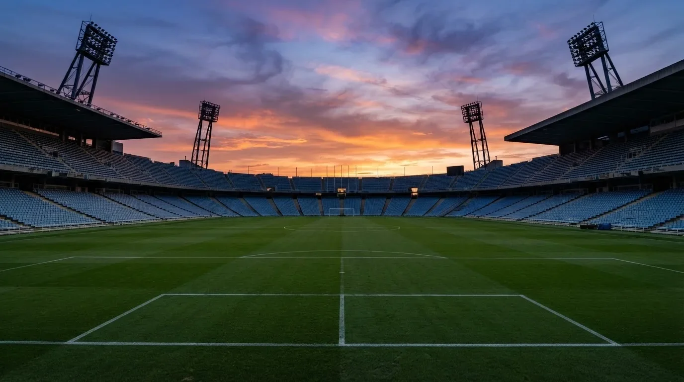 Un estadio de fútbol vacío con torres de iluminación al atardecer