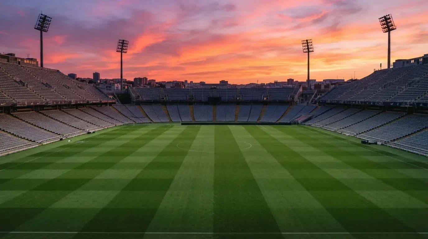 Un estadio de fútbol vacío con torres de iluminación al atardecer