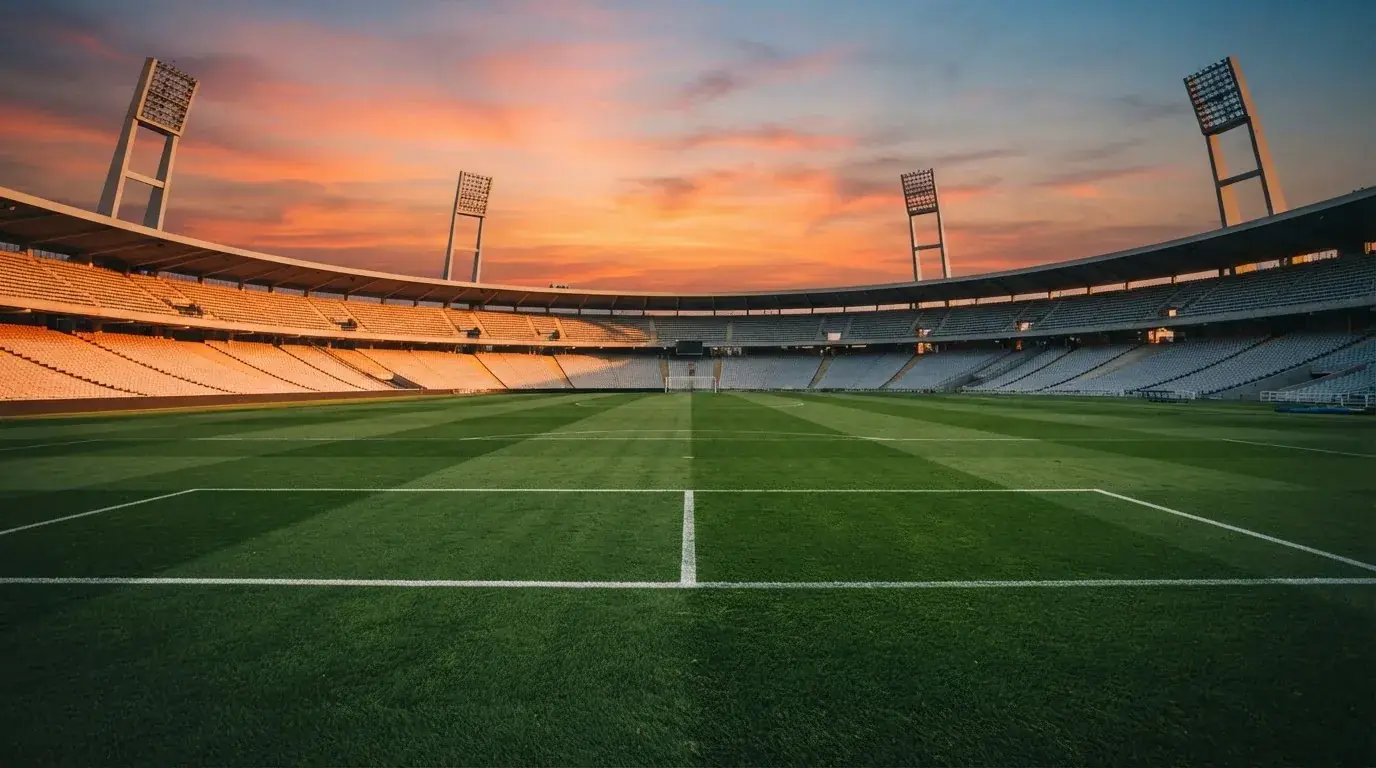 Un estadio de fútbol vacío con torres de iluminación al atardecer