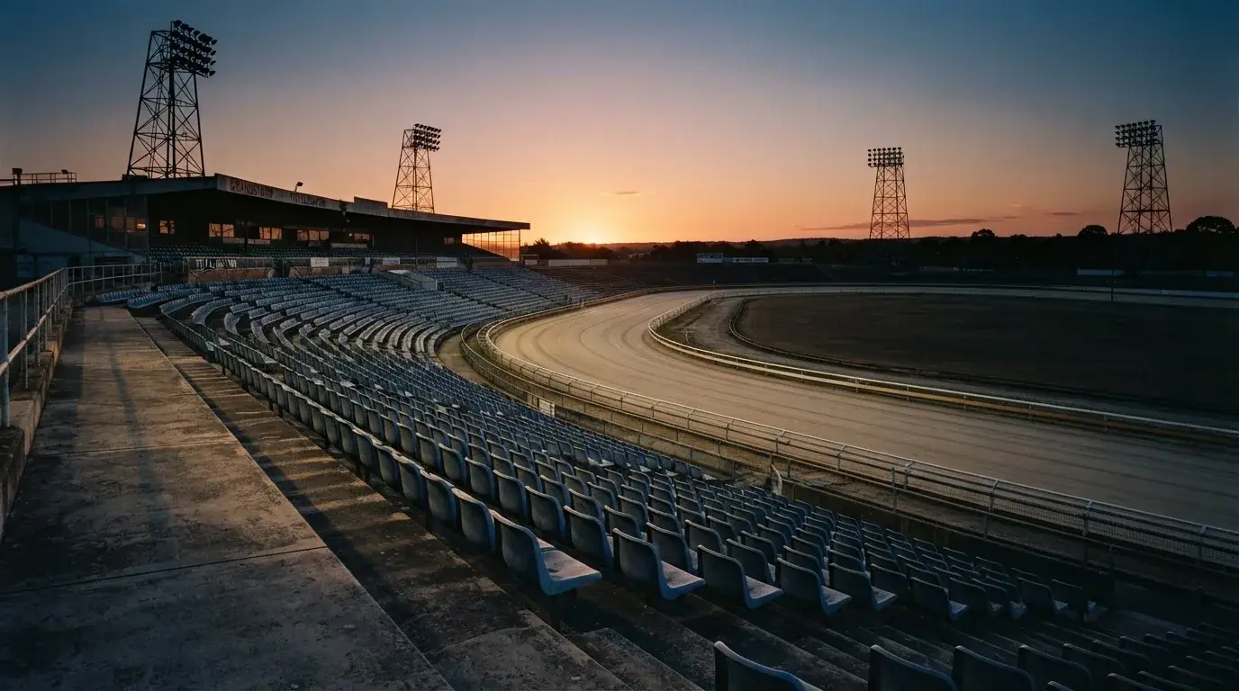 Un estadio de fútbol vacío con torres de iluminación al atardecer