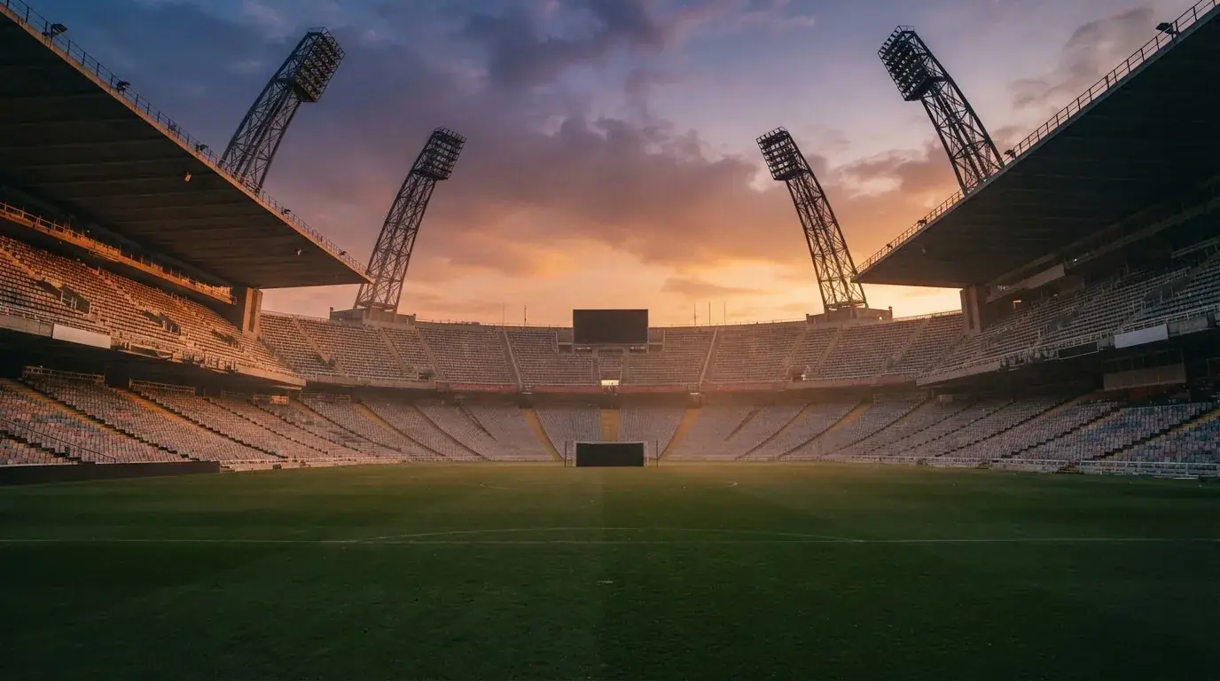 Un estadio de fútbol vacío con torres de iluminación al atardecer