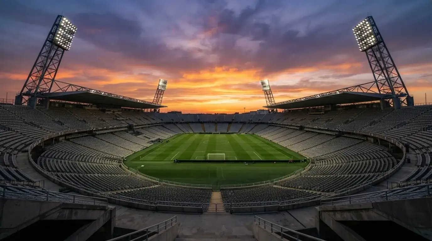 Un estadio de fútbol vacío con torres de iluminación al atardecer