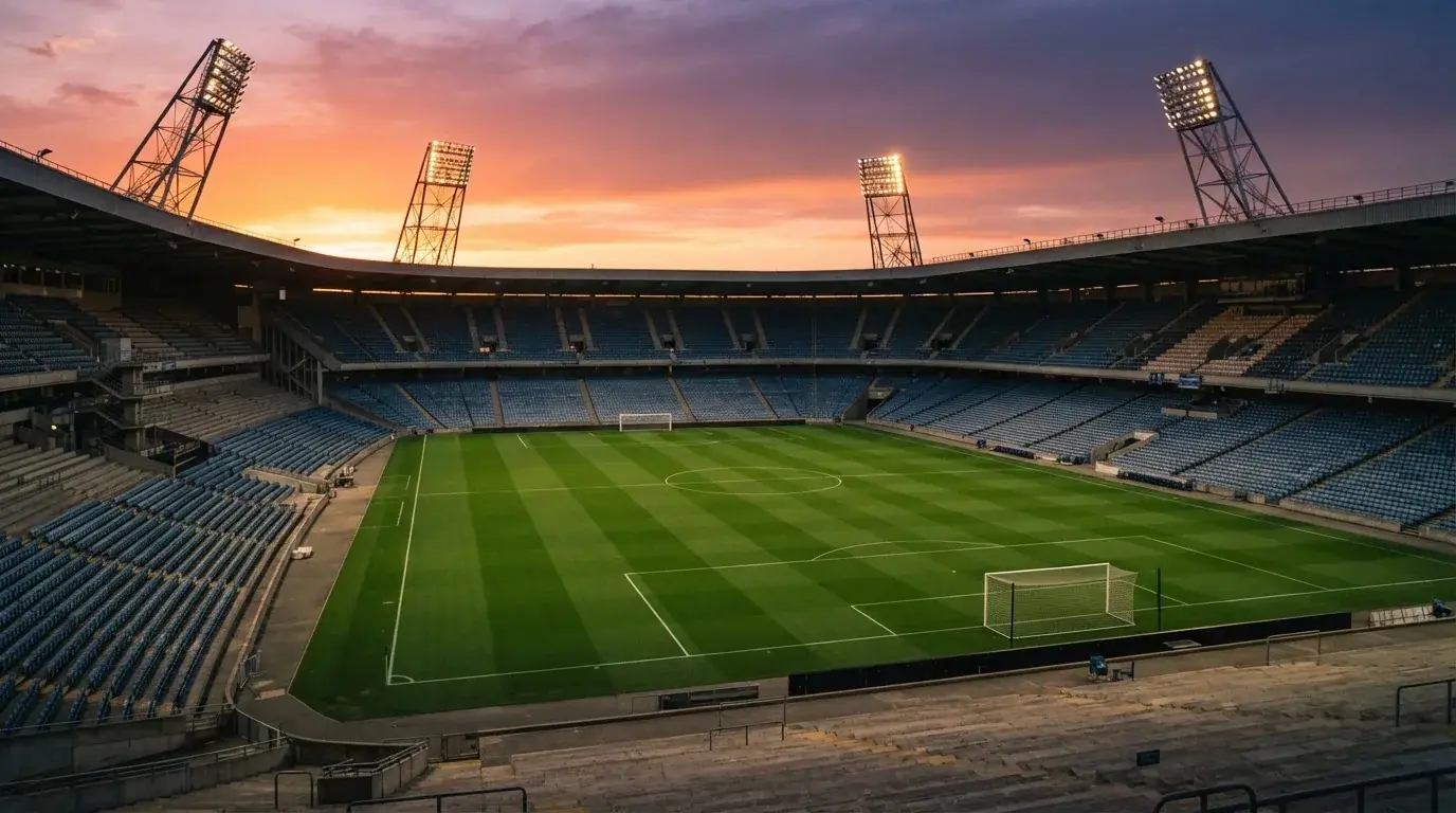 Un estadio de fútbol vacío con torres de iluminación al atardecer