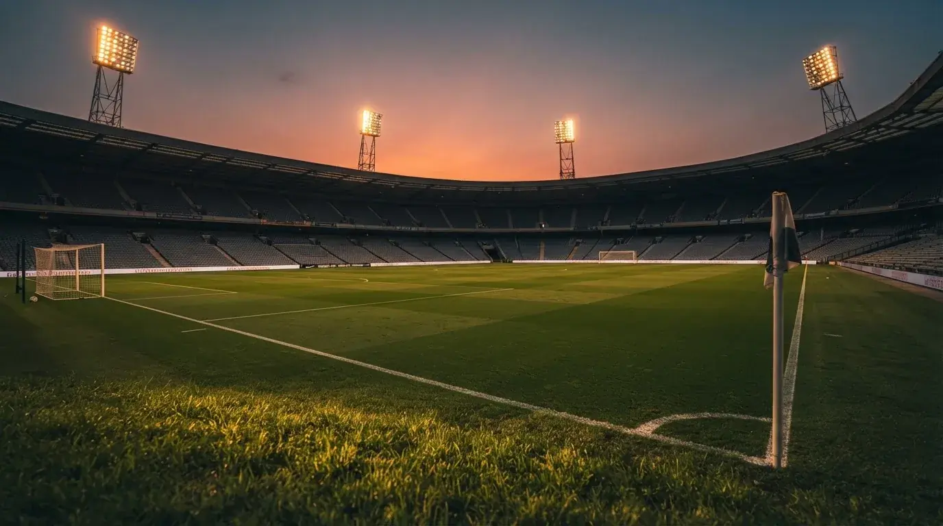 Un estadio de fútbol vacío con torres de iluminación al atardecer