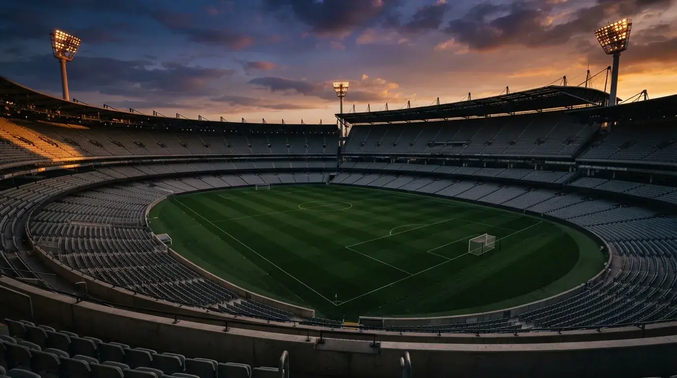 Un estadio de fútbol vacío con torres de iluminación al atardecer