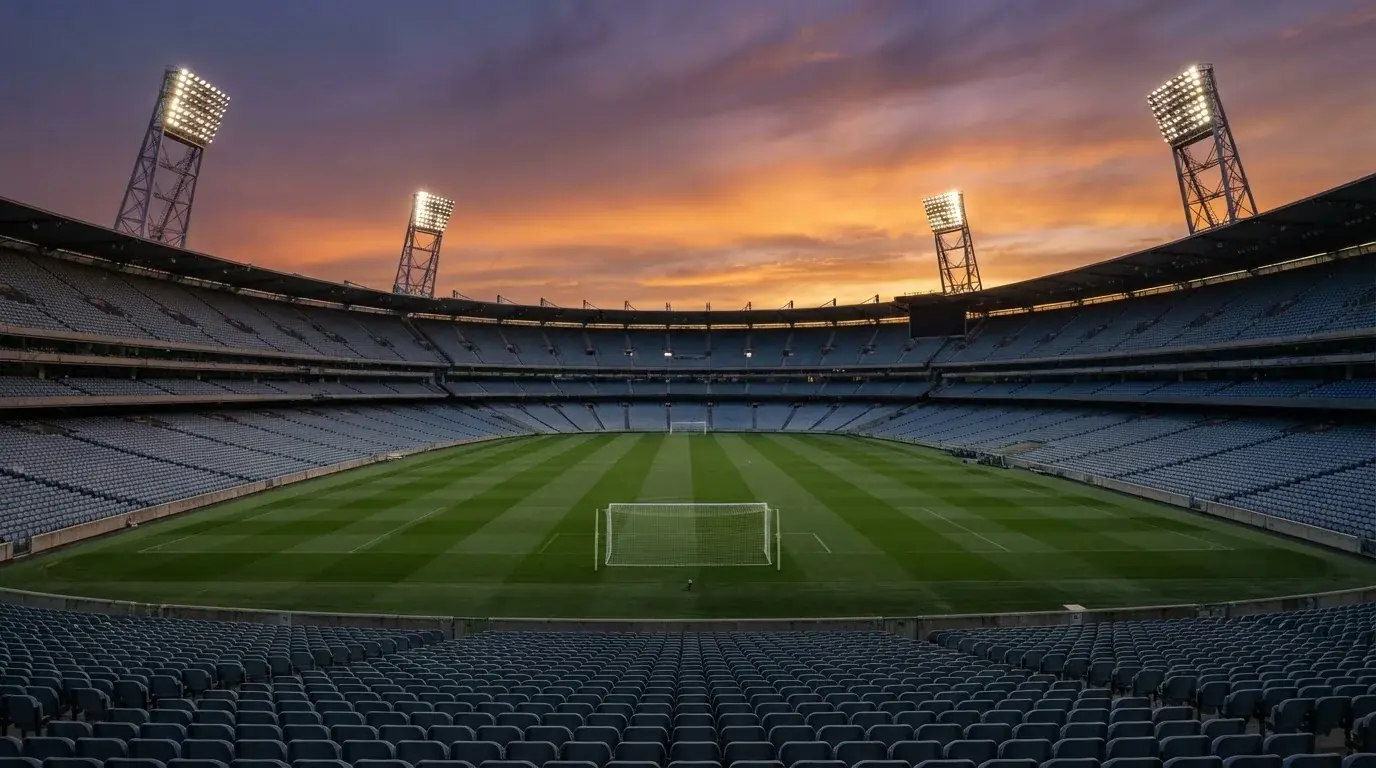 Un estadio de fútbol vacío con torres de iluminación al atardecer