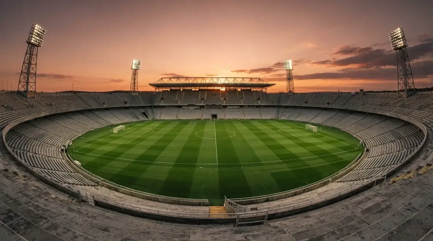 Un estadio de fútbol vacío con torres de iluminación al atardecer
