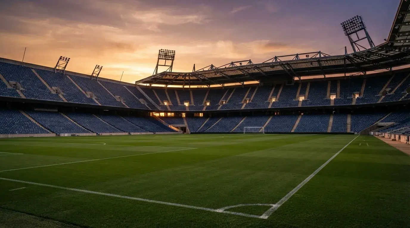 Un estadio de fútbol vacío con torres de iluminación al atardecer
