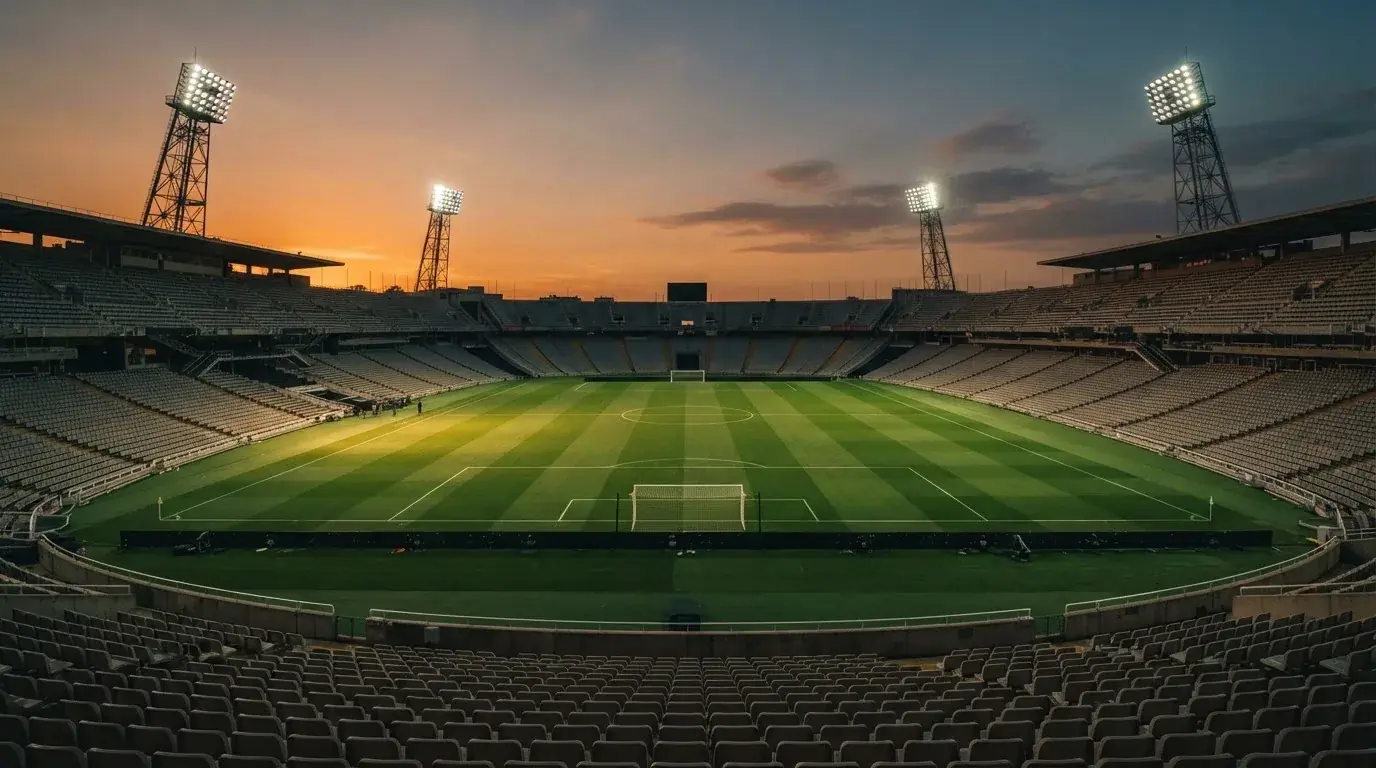 Un estadio de fútbol vacío con torres de iluminación al atardecer