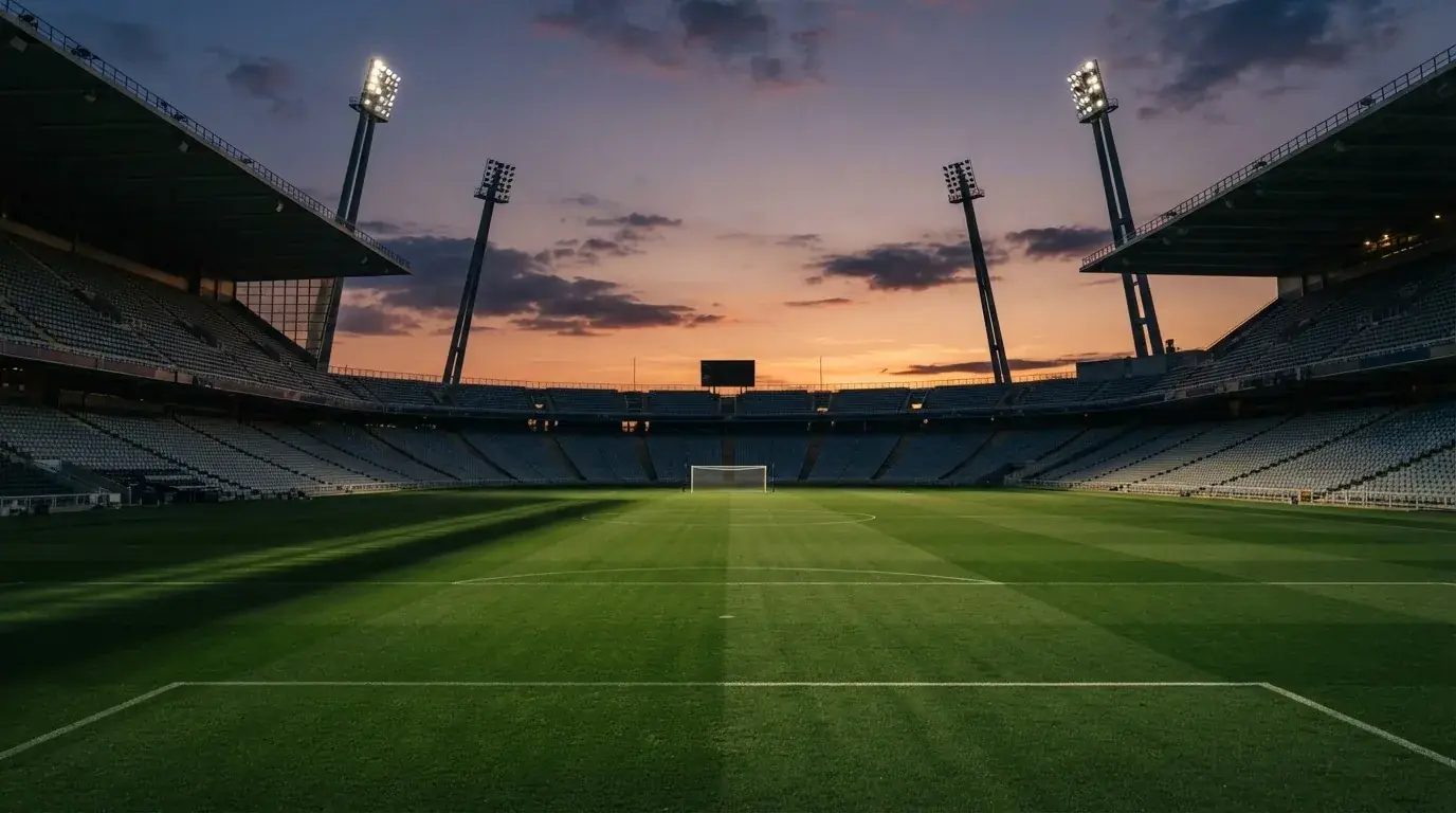 Un estadio de fútbol vacío con torres de iluminación al atardecer