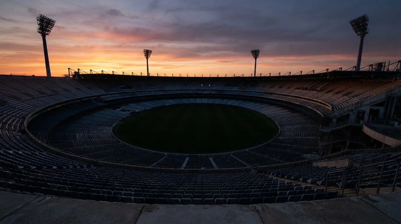 Un estadio de fútbol vacío con torres de iluminación al atardecer