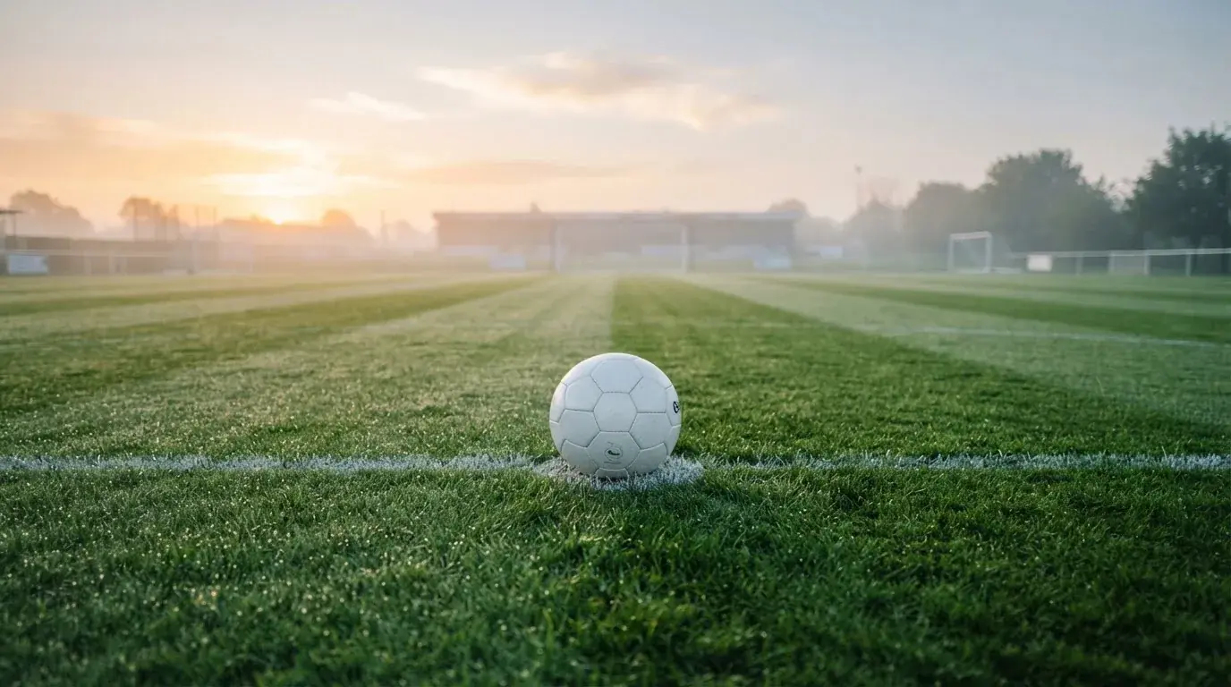 Un balón en el punto central de un campo de césped a la luz de la mañana