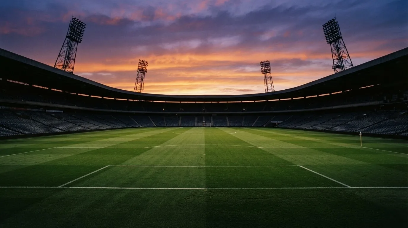 Un estadio de fútbol vacío con torres de iluminación al atardecer